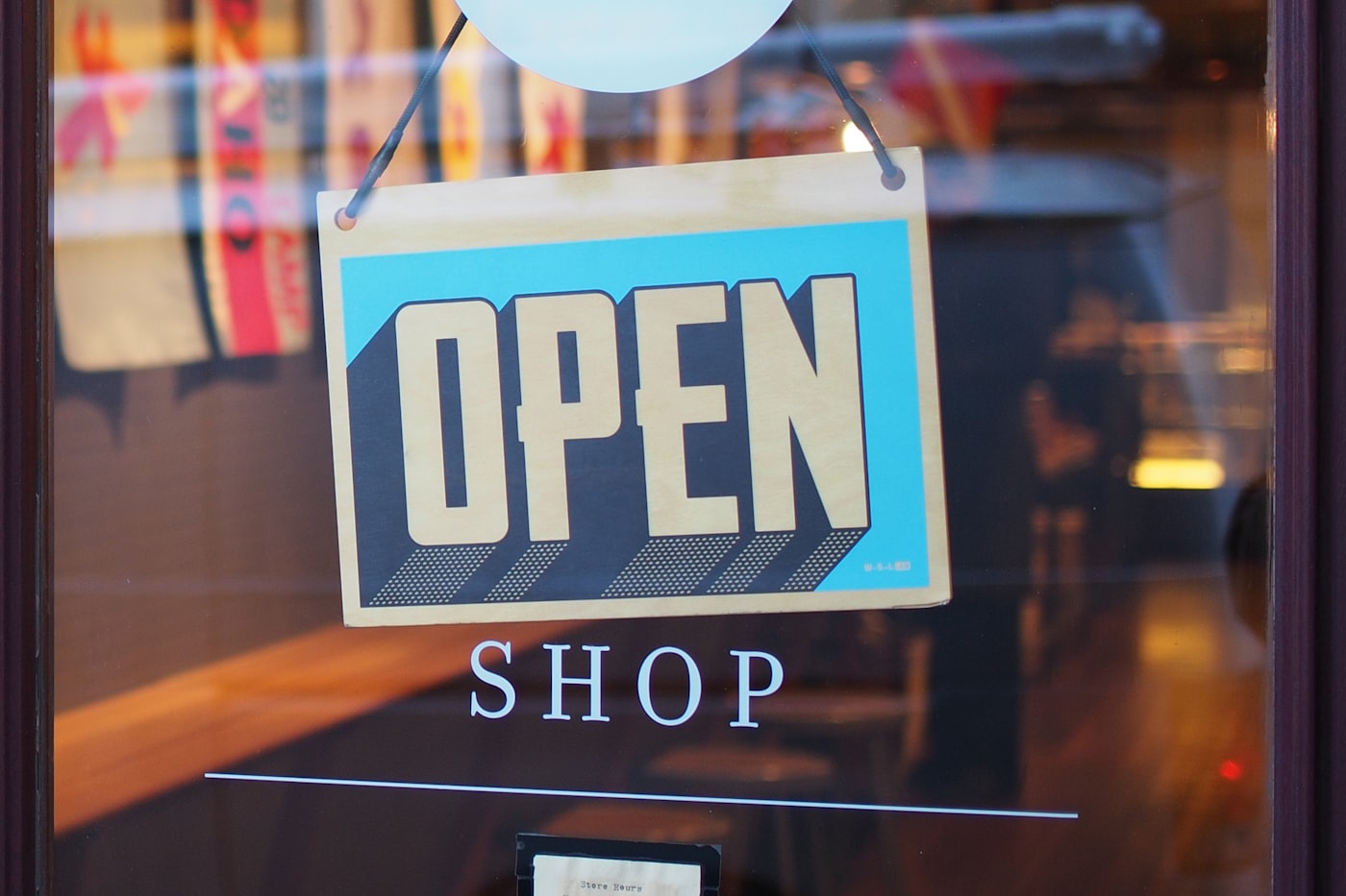 An OPEN SHOP sign hanging in a shop door